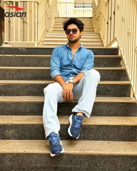 Model posing in stylish sports sneaker for men.